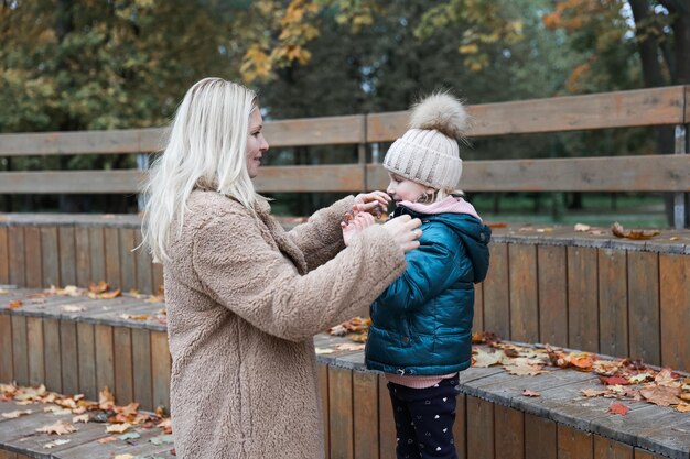 La madre e la figlia della famiglia felice sono nel parco cittadino d'autunno Posano sorridendo giocando e divertendosi Alberi gialli luminosi