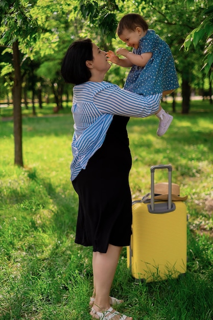 La madre e la figlia si stanno preparando per il viaggio una bambina si siede su una valigia gialla