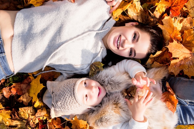 La madre e la figlia si trovano sulle foglie di autunno