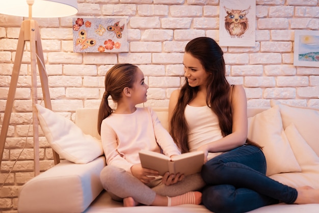 La madre e la figlia sono libro di lettura sul computer portatile.