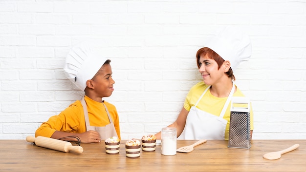 La madre e suo figlio vestiti come chef in una cucina