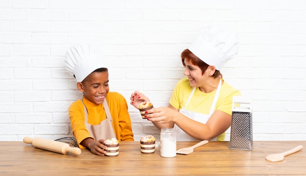 La madre e suo figlio vestiti come chef in una cucina