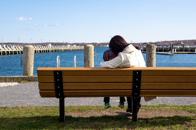 La madre ed il figlio che si siedono su un banco esaminano il paesaggio dell&#39;oceano