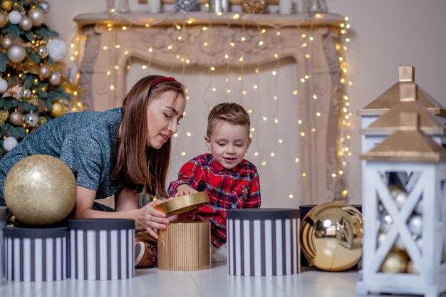 La madre fa un regalo di Natale al figlio piccolo per un nuovo anno. Mamma e figlio che aprono i regali di Natale