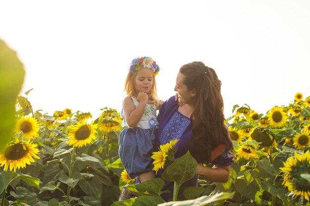 La madre felice abbraccia sua figlia in un campo di girasoli