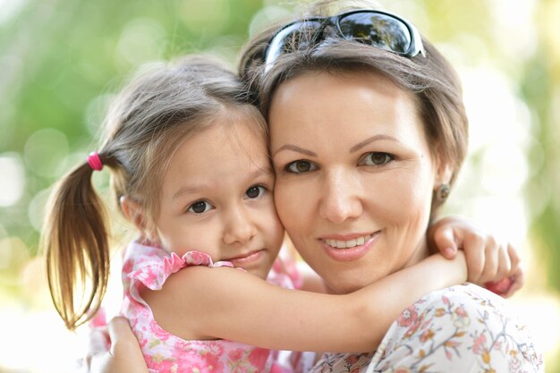 La madre felice con sua figlia cammina nel parco estivo