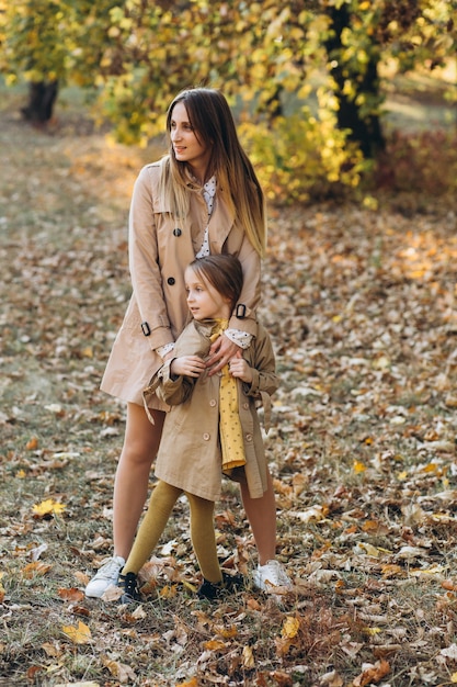 La madre felice e la sua bella figlia si divertono e camminano nel parco d'autunno.