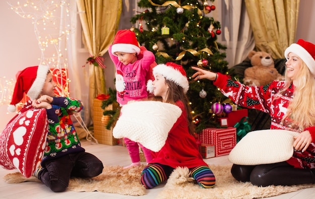 La madre gioca con i bambini alla festa serale di Chrismtas, i bambini si tengono per mano il cuscino da battaglia, l'ora del pavimento