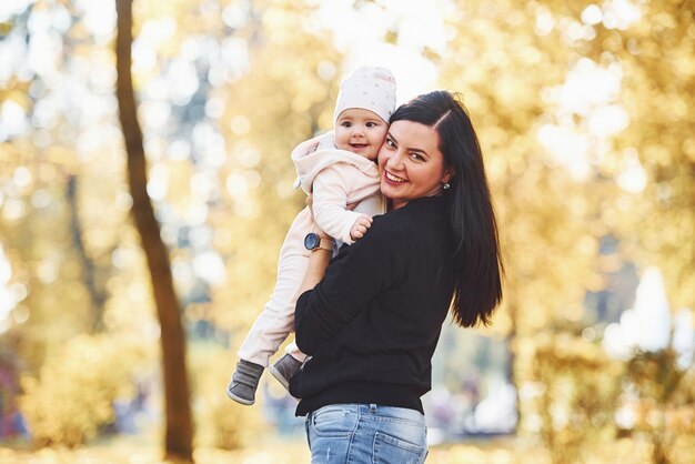 La madre in abiti casual con il suo bambino è nel bellissimo parco autunnale.