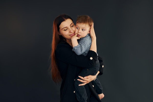 La madre in eleganti abiti neri è con il suo piccolo figlio in studio