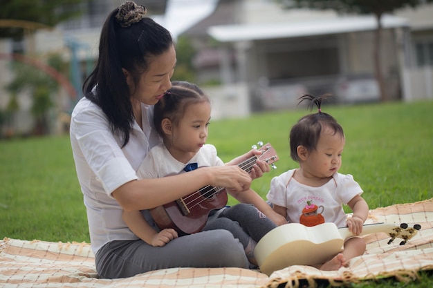 La madre insegna a sua figlia a suonare l'ukulele sul prato del giardino