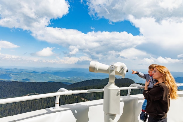 La madre mostra i paesaggi del figlio nella valle dei Monti Rodopi e il cielo attraverso il telescopio sulla torre di osservazione di Snezhan