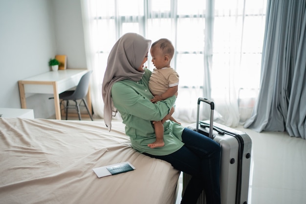 La madre musulmana trasporta il suo bambino mentre è seduta sul letto