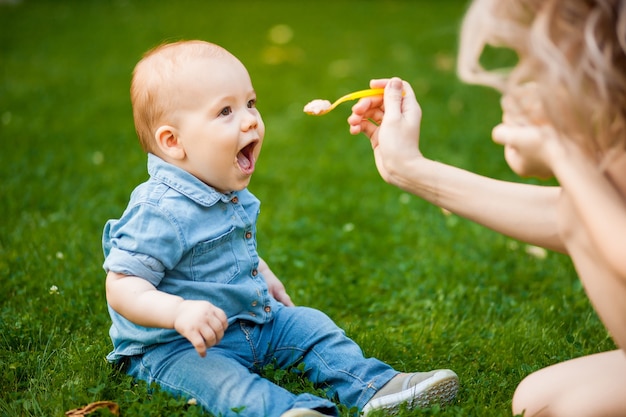 La madre nutre il bambino con un cucchiaio nel parco