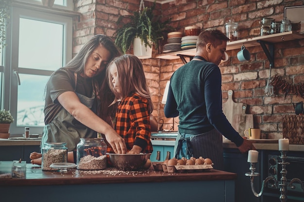 La madre pensierosa e la sua piccola figlia stanno cucinando qualcosa insieme in cucina.