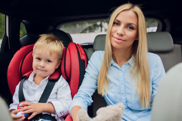 La madre si è preoccupata per la sicurezza dei suoi figli in un'auto Figlio vicino alla mamma Ragazze sedute all'interno dell'auto moderna Le persone guardano fotocamera L'idea di un traffico sicuro