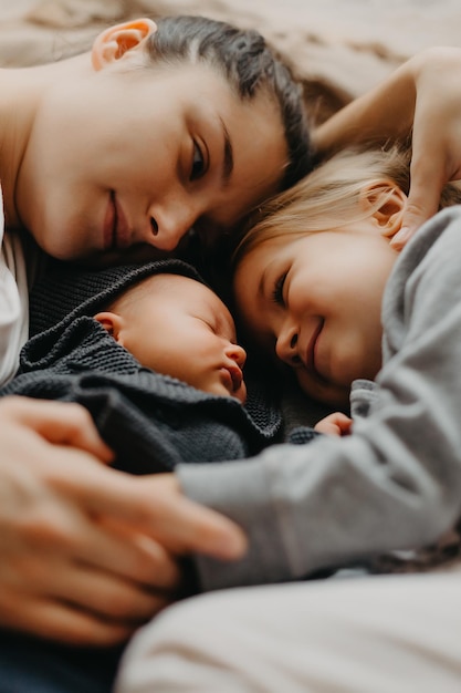 La madre si è sdraiata a dormire accanto alle sue figlie Foto di casa dei bambini con la mamma che si è addormentata abbracciata