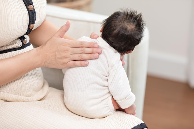 La madre si prende cura del suo neonato Il singhiozzo per far ruttare il bambino può ridurre l'aria nello stomaco Il bambino neonato singhiozza dopo aver nutrito troppo latte Il concetto di cura sanitaria del bambino neonato