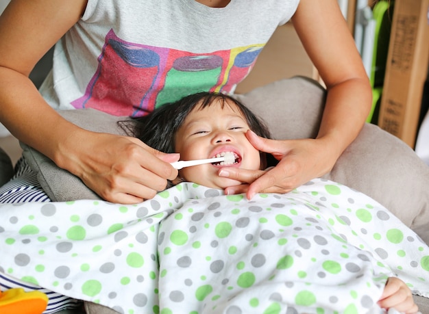 La madre sta aiutando a spazzolare i suoi denti da latte