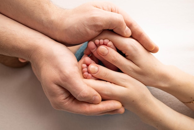 La madre sta facendo un massaggio sul suo piede del bambino Primo piano dei piedi del bambino nelle mani della madre su uno sfondo bianco Prevenzione dello sviluppo dei piedi piatti displasia del tono muscolare Famiglia amore cura e concetto di salute