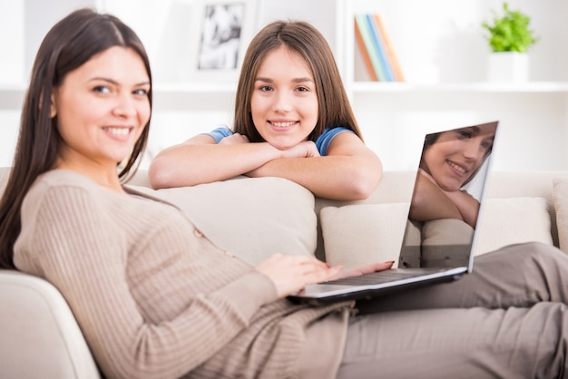 La madre sta usando il computer portatile mentre era seduto sul divano.