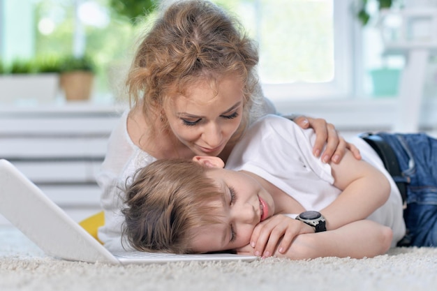 La madre sveglia il figlioletto che dorme sul pavimento vicino al laptop
