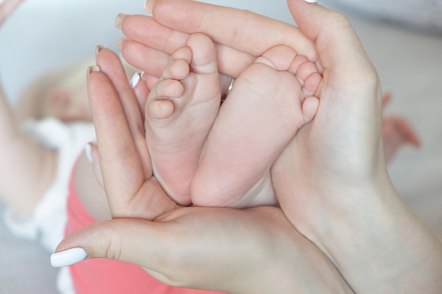 La madre tiene i piedini del bambino nella mano della donna