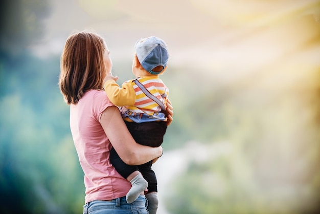 La madre tiene il bambino tra le mani sullo sfondo della natura