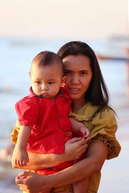 La madre tiene il suo bambino e sta passeggiando per la spiaggia