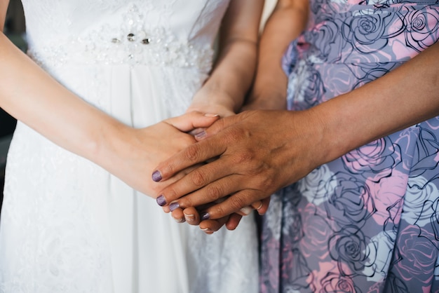 La madre tiene la sposa della figlia per le mani il giorno del matrimonio