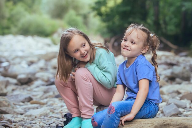 La mamma a casa sul divano legge un libro alle sue piccole figlie, sono avvolte in una coperta