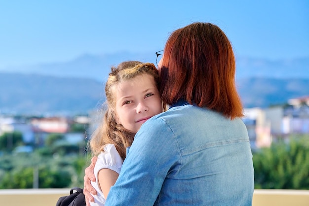 La mamma abbraccia la figlia preadolescente sotto il portico di casa