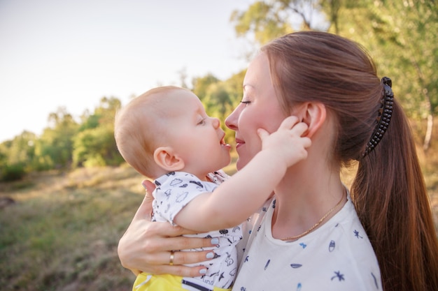 La mamma abbraccia un servizio fotografico estivo per bambini piccoli, il bambino bacia la mamma