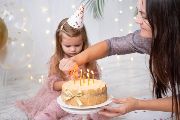 La mamma accende le candeline sulla torta di compleanno alla bambina carina