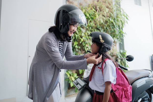 La mamma accompagna la figlia a scuola in moto al mattino