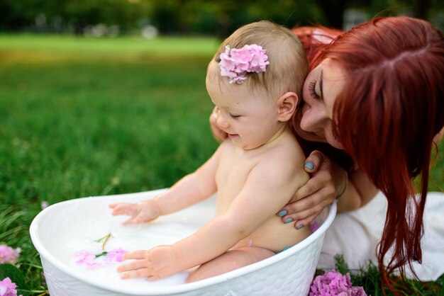 La mamma aiuta la figlia di un anno a fare il bagno in bagno. Girato in un parco all'aperto nella natura.