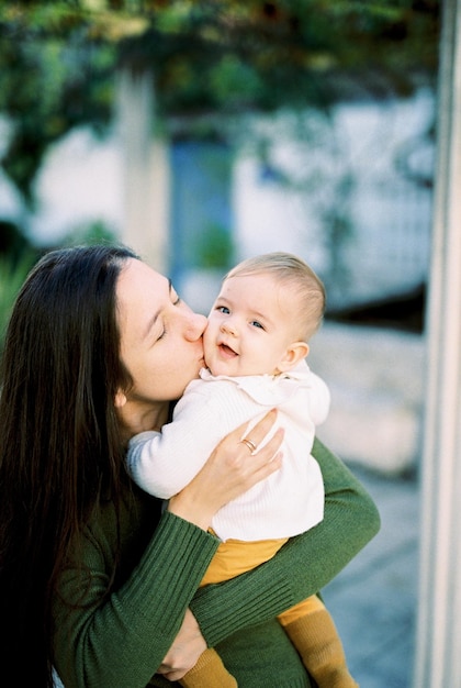 La mamma bacia un bambino sorridente tra le sue braccia