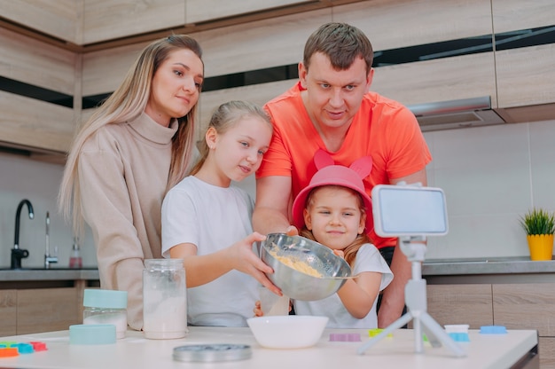 La mamma con il padre insegna a due figlie a cucinare la pasta in cucina.