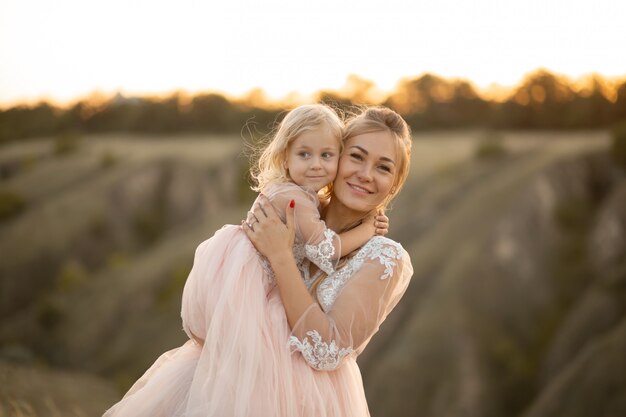 La mamma con la figlia in abiti da fiaba rosa cammina nella natura