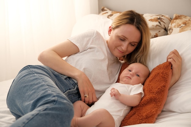 La mamma con un neonato giace sul letto la madre bacia l'amore della madre del bambino