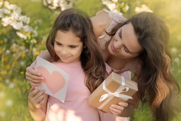 La mamma dà a sua figlia un biglietto e un regalo.