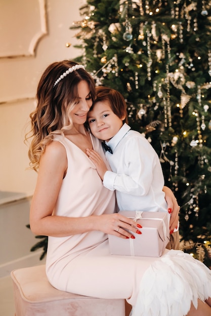 La mamma dà a suo figlio un regalo di Natale vicino all'albero di Natale. Famiglia felice.