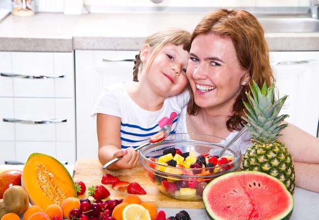 La mamma dà alla bambina una macedonia di frutta in cucina.