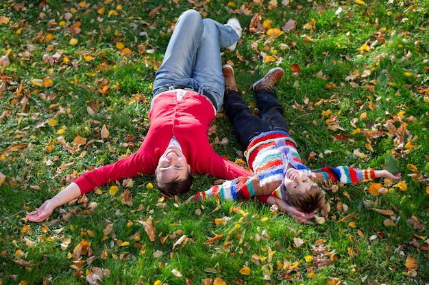 La mamma e il piccolo giacciono sull'erba nel parco autunnale