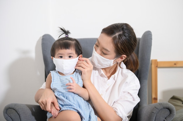 La mamma e la figlia asiatiche indossano la maschera protettiva