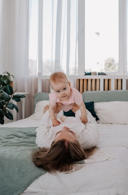 La mamma è sdraiata sul letto e solleva la bambina