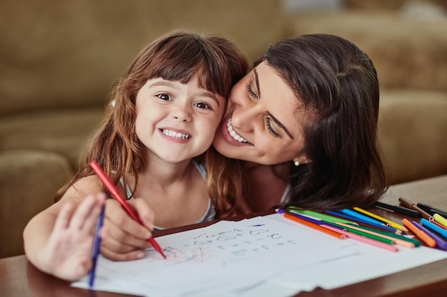 La mamma fa il miglior insegnante di sempre Ritratto di una giovane donna che disegna insieme alla sua giovane figlia a casa