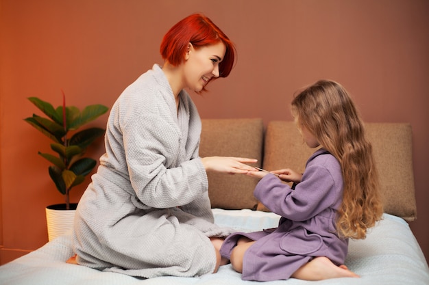 La mamma fa la figlia sul letto a casa manicure