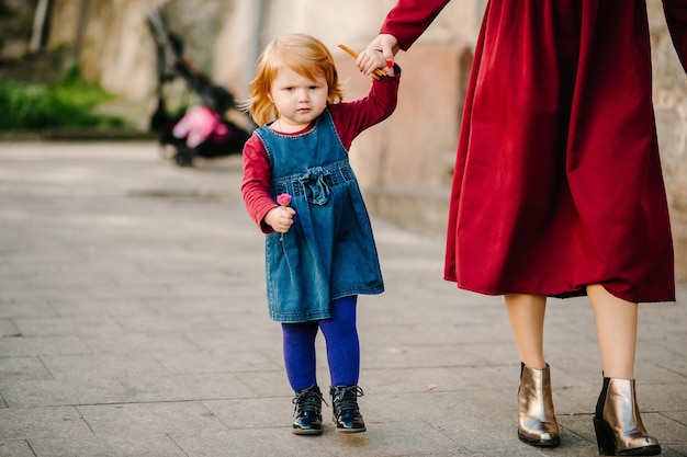 La mamma felice della famiglia tiene la figlia con il fiore che si gode il tempo insieme camminando sulla città di strada nel paese Europa