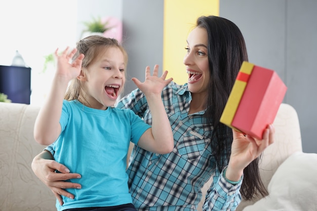 La mamma felice estatica con la figlia tiene il primo piano del contenitore di regalo